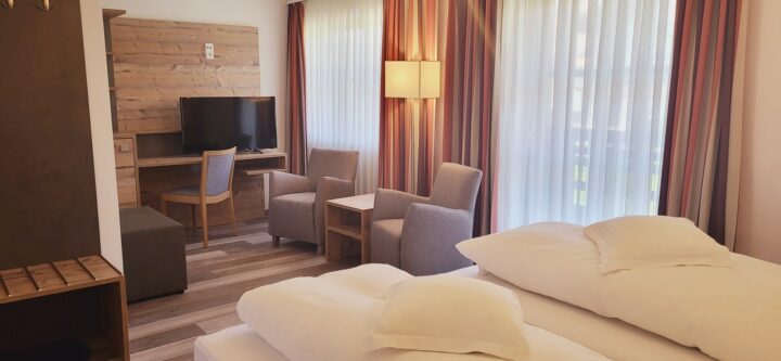 Komfort-Zimmer mit Doppelbett und Sessel im Hotel Geiger am Hopfensee